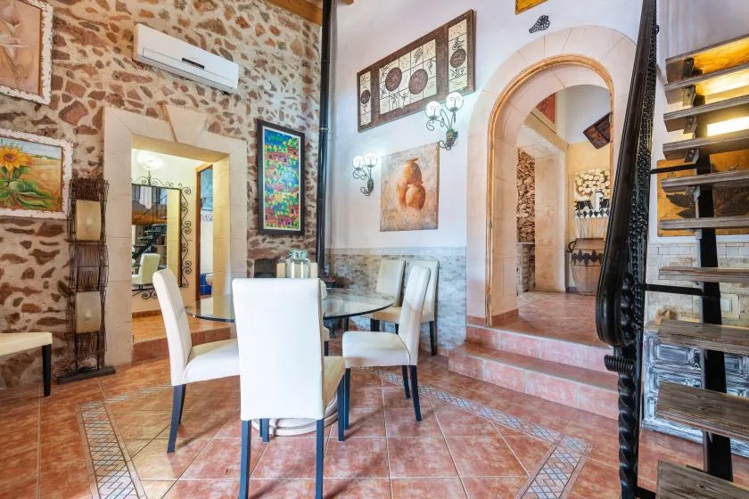 Comedor con mesa y sillas junto a una pared de aspecto pétreo y un arco.