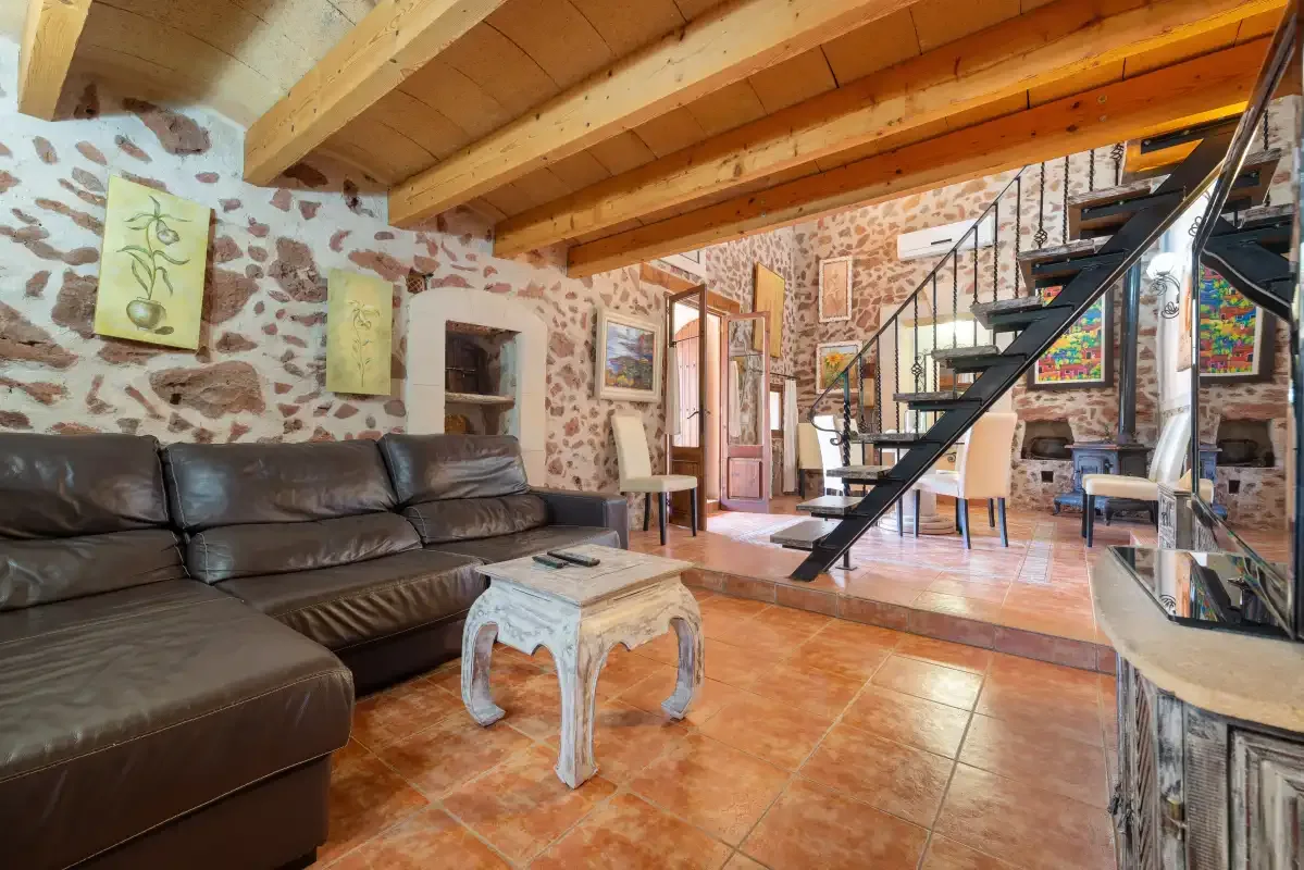 Una sala de estar con asientos oscuros, una mesa de centro y una escalera.