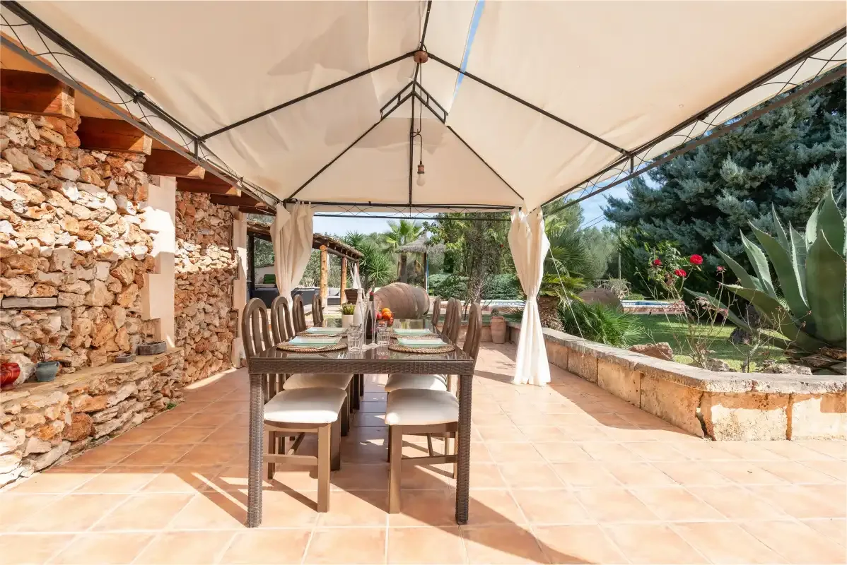 Una zona de comedor exterior cubierta con una mesa y sillas junto a un muro de piedra.