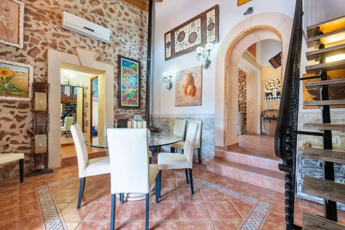 Un comedor rústico con una mesa y sillas junto a una pared de piedra.