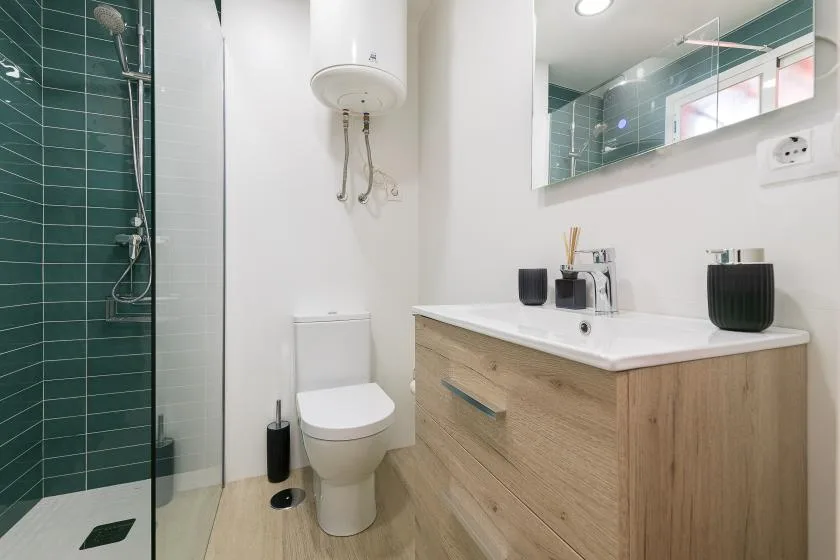 A bathroom with a glass shower, toilet, and wood-toned vanity.