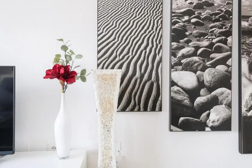 A bright interior wall displays framed monochrome nature prints beside a vase of flowers.