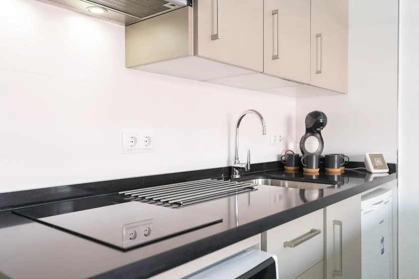 A modern kitchen with a black countertop, cooktop, and sink.