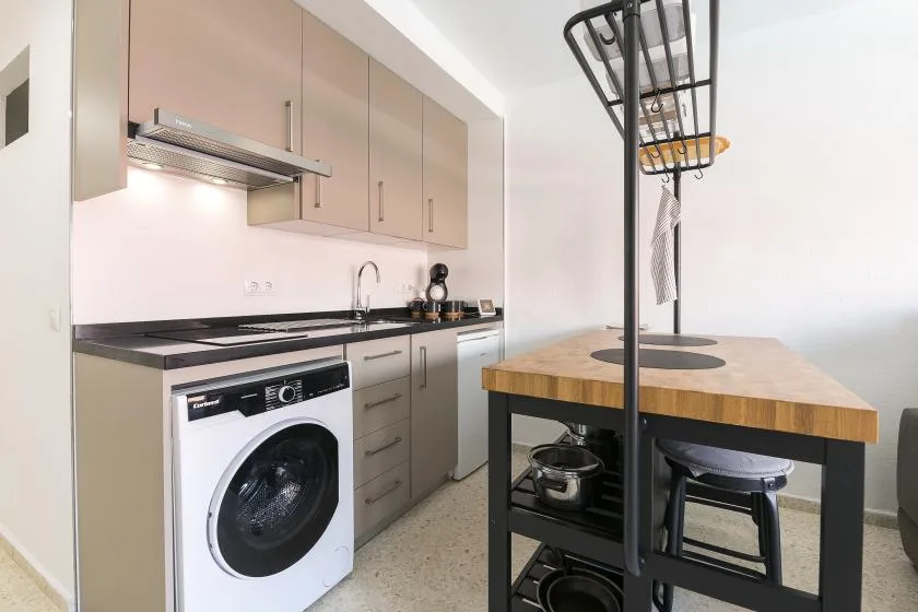 A compact kitchen with cabinets, a cooktop, and a wooden island.