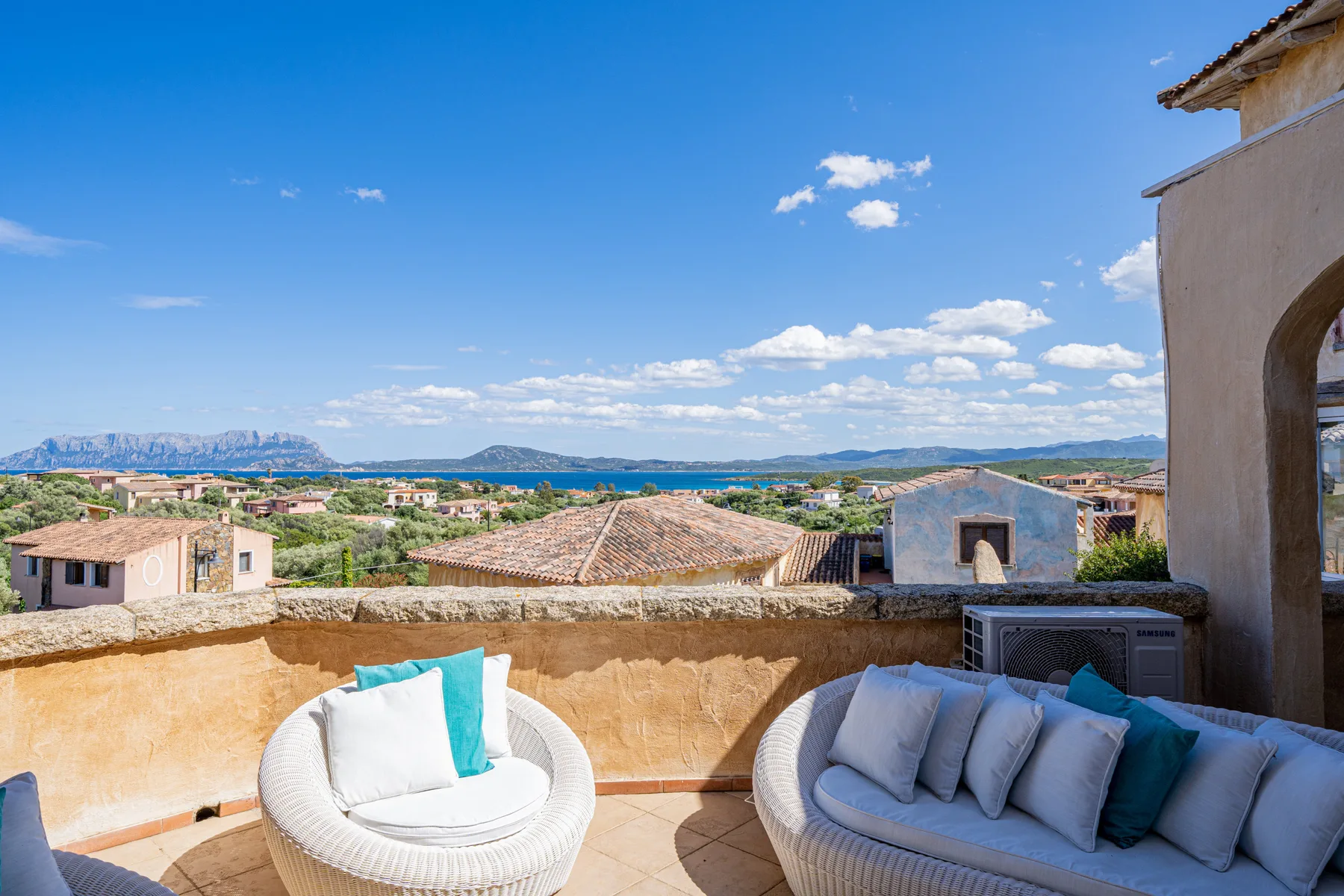 Una terraza soleada con asientos acolchados y vistas al mar.