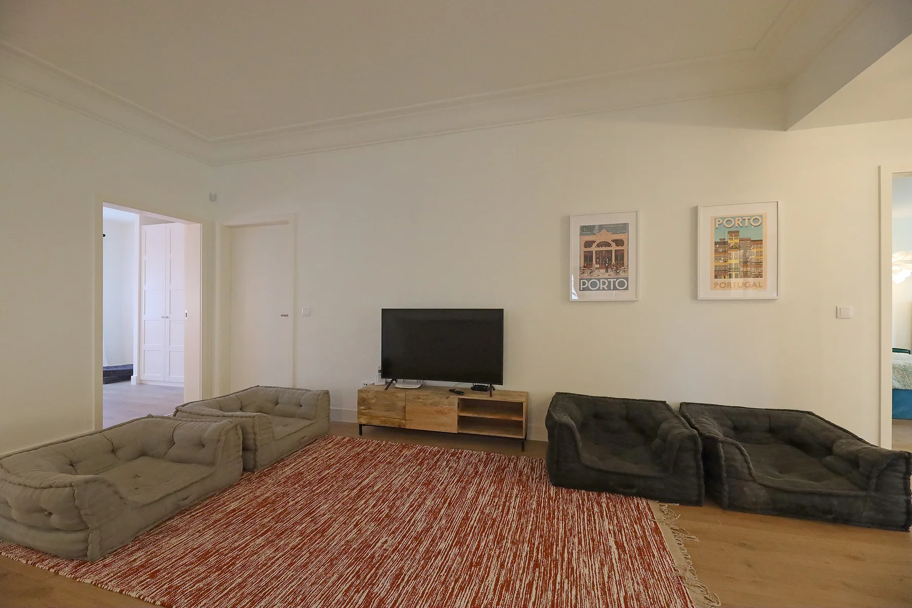 A living room with two seating areas, a television, and framed wall prints.