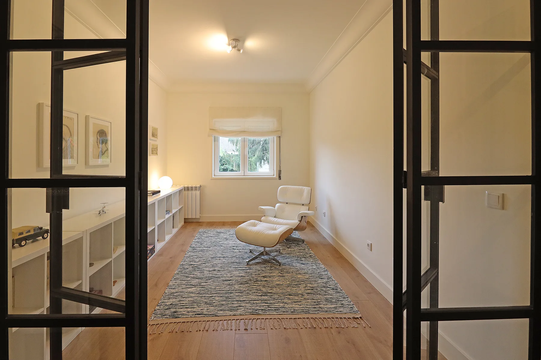 A bright sitting room with a rug, lounge seating, and a window.