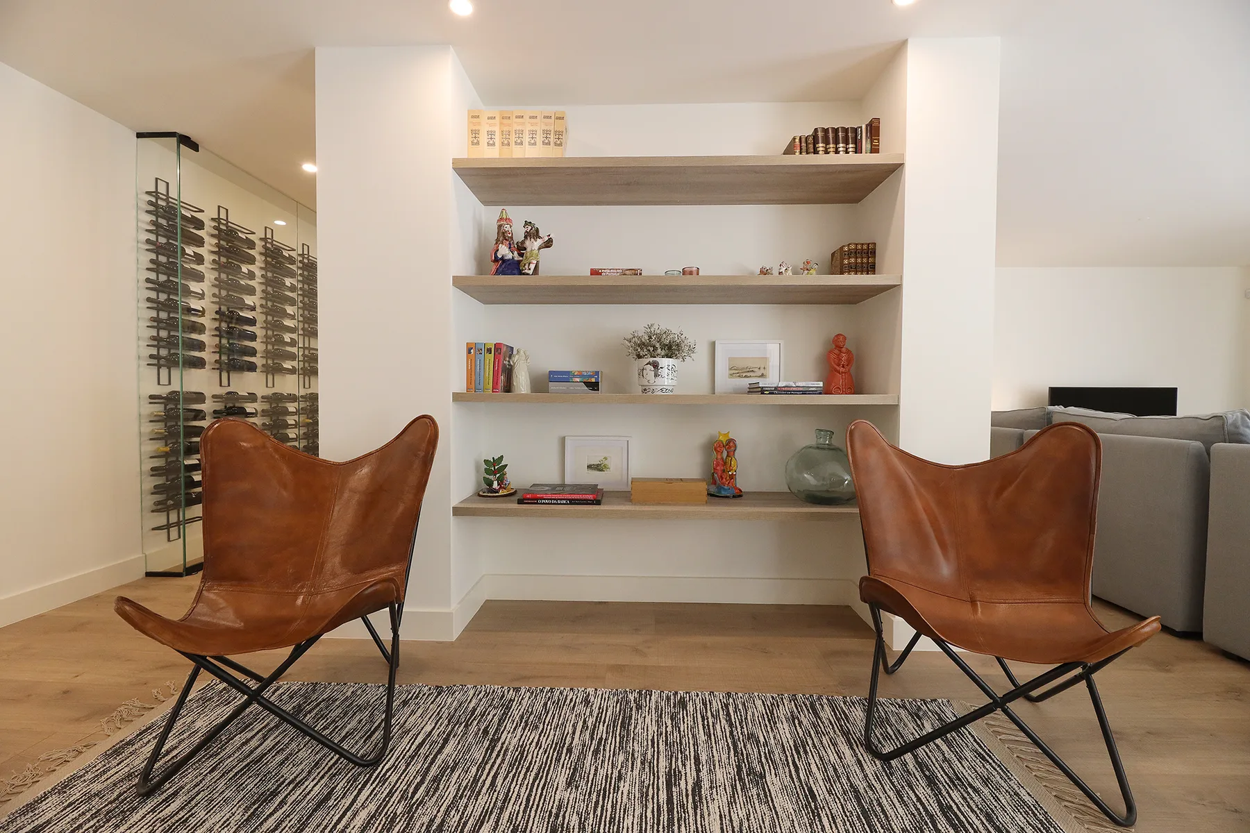 A living room with two leather seats facing built-in display shelves.