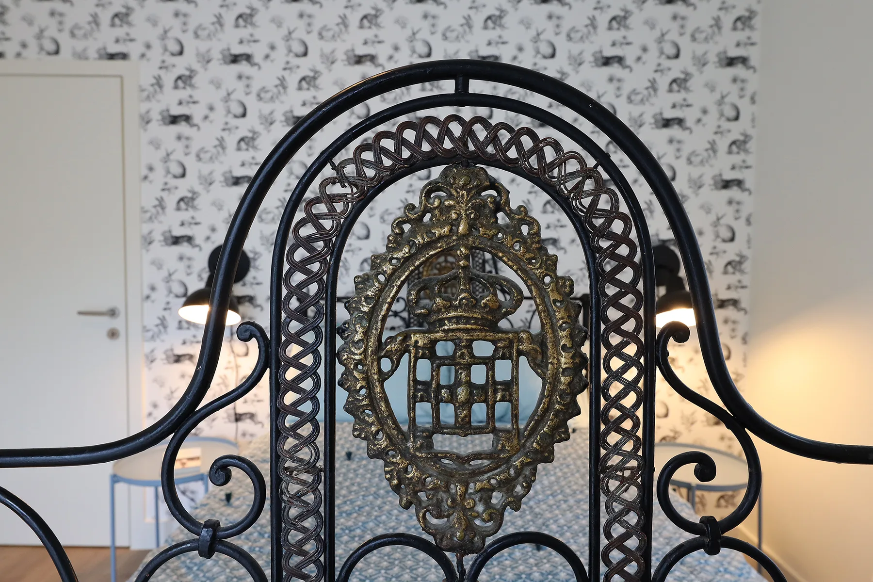 An ornate black metal railing stands against patterned wallpaper.