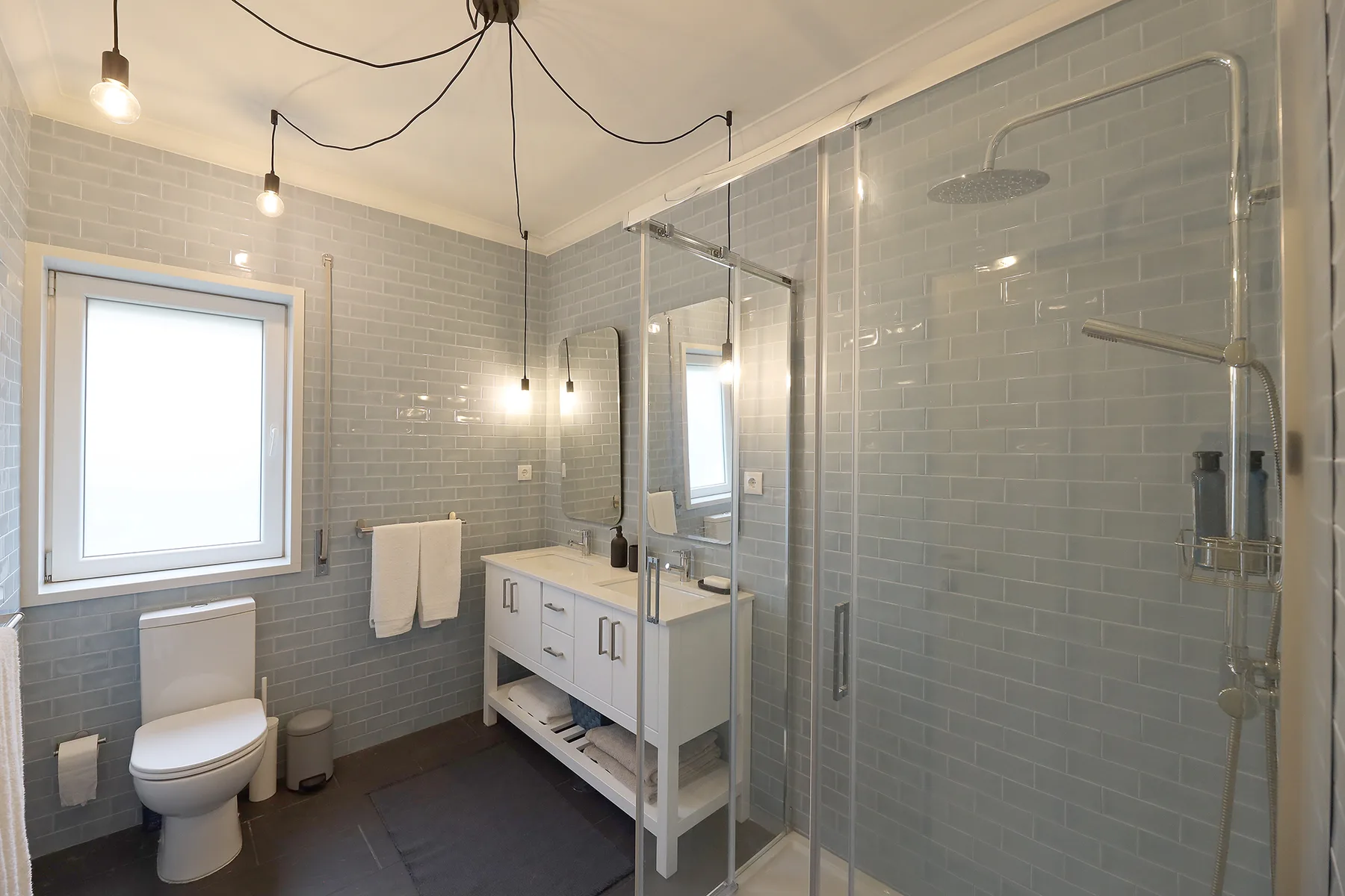A tiled bathroom with a vanity, toilet, and glass shower.