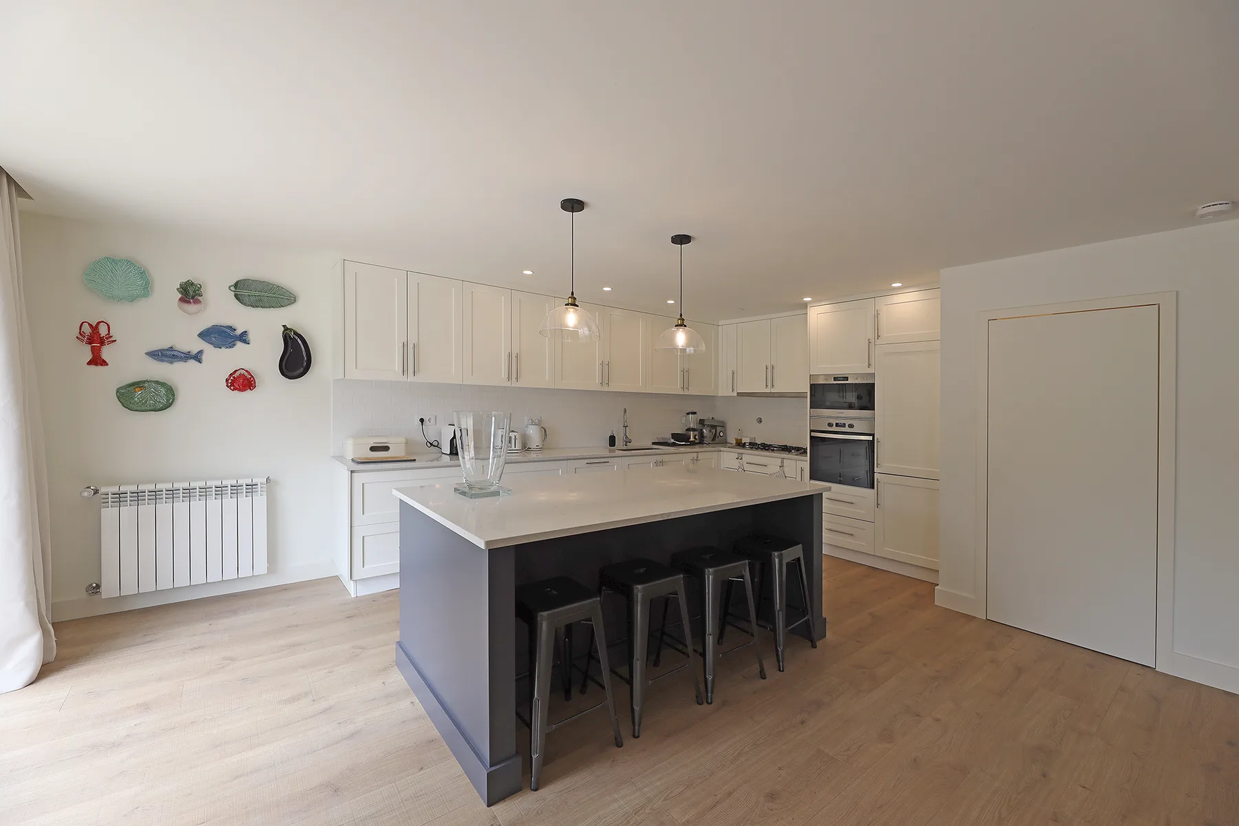 A bright kitchen with an island, bar seating, and white cabinetry.