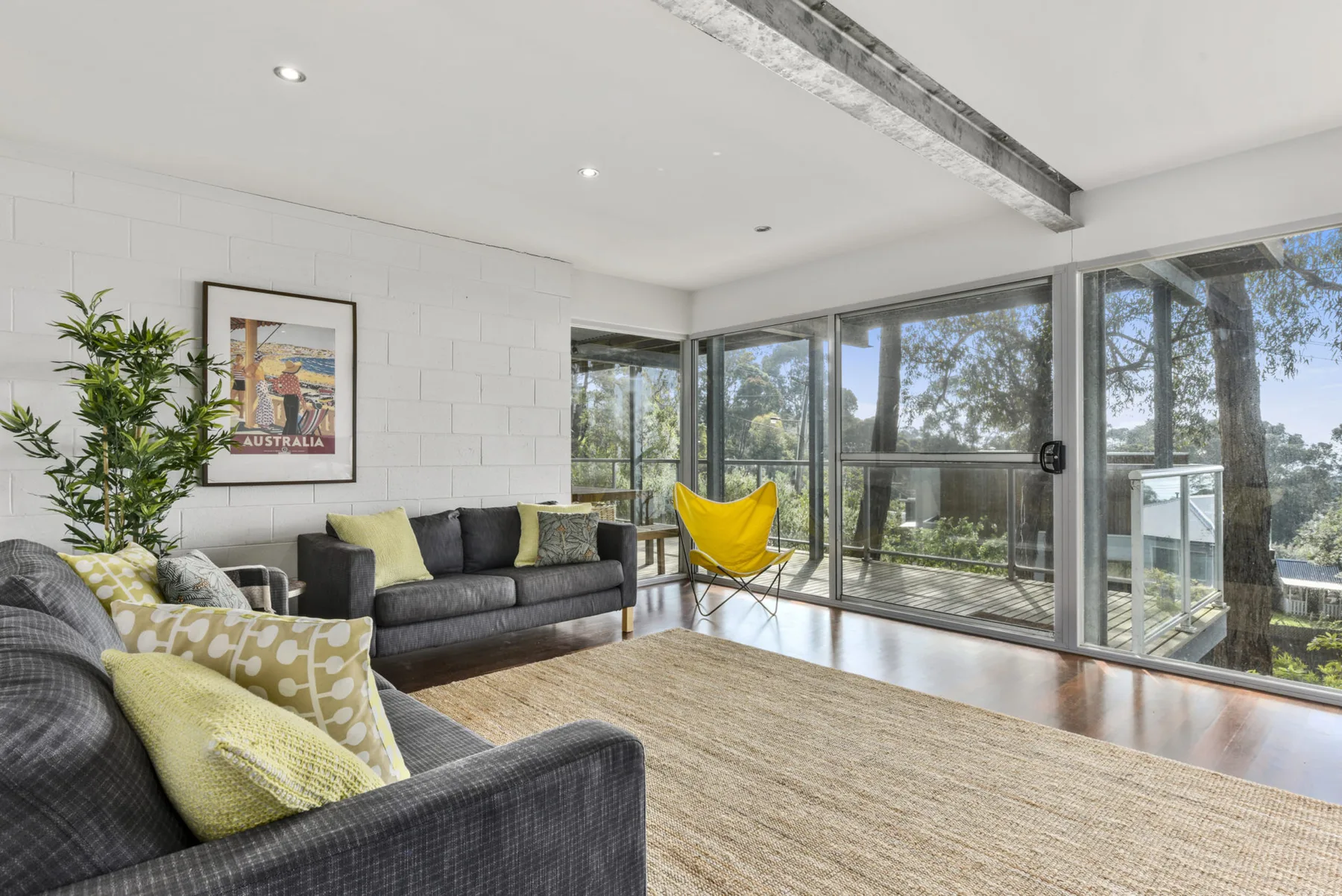 A bright living room with seating beside large windows and a yellow hammock chair.