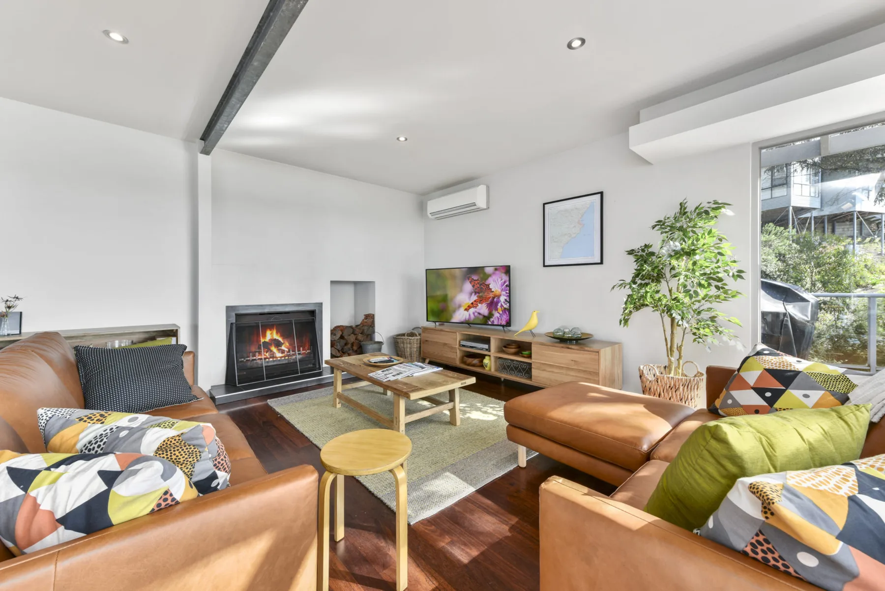 A bright living room with seating arranged around a fireplace and television.