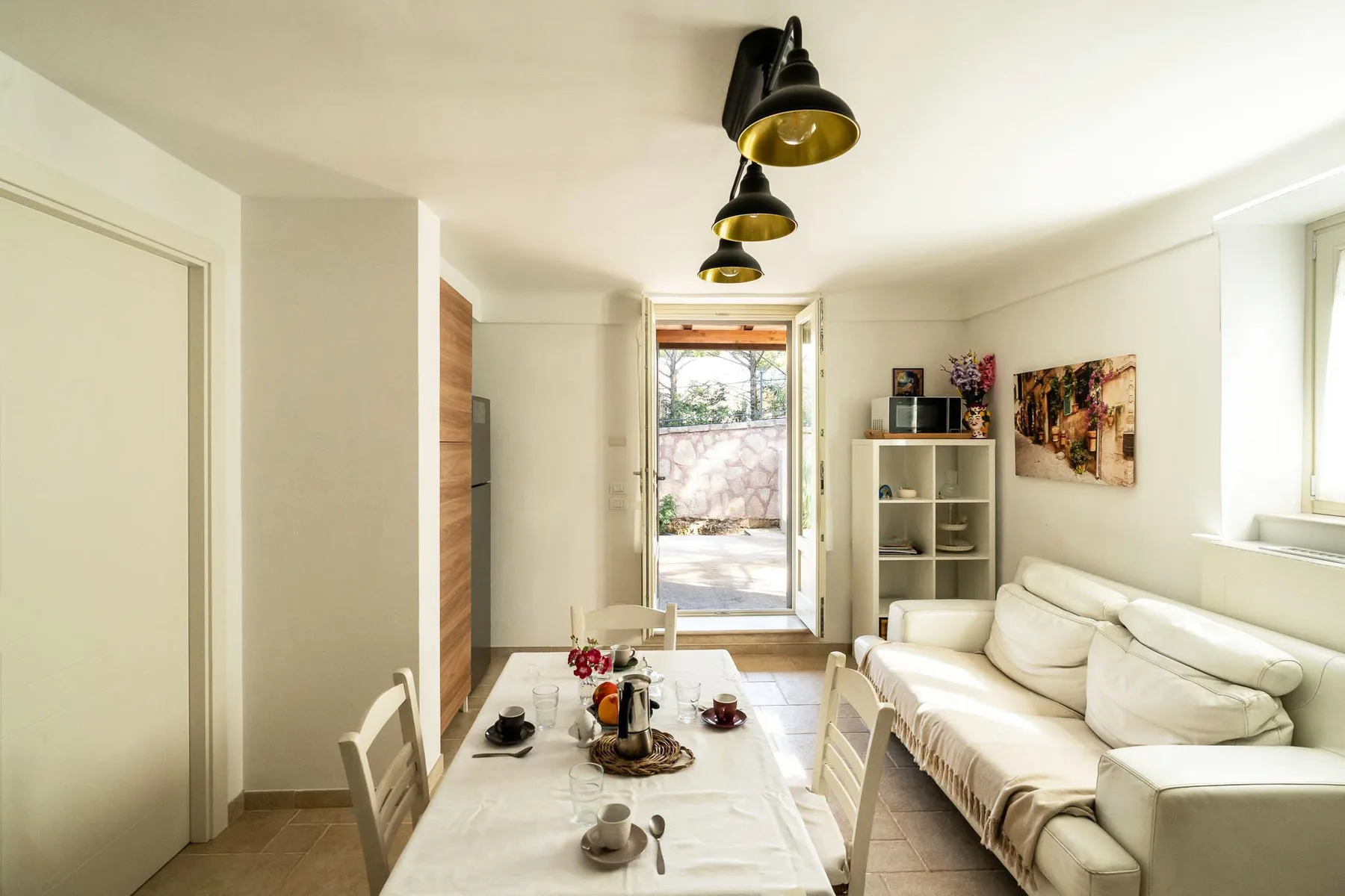 A bright living room with seating around a dining table and a large window.