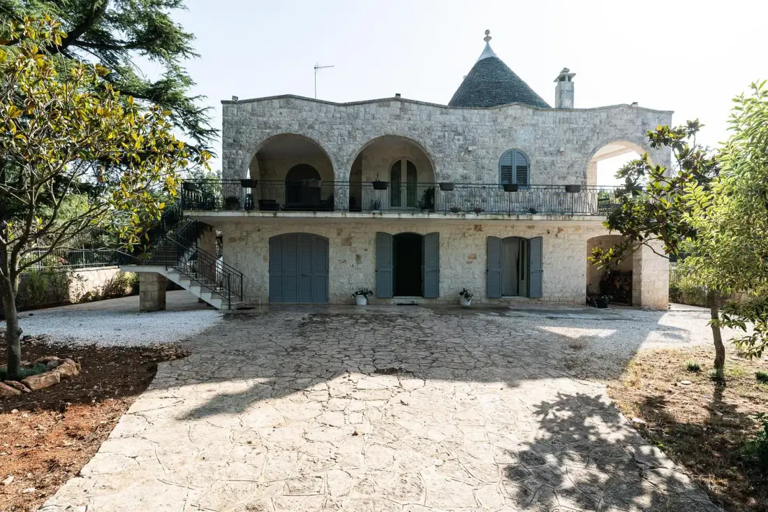 A stone building with an upper terrace overlooks a broad paved courtyard.