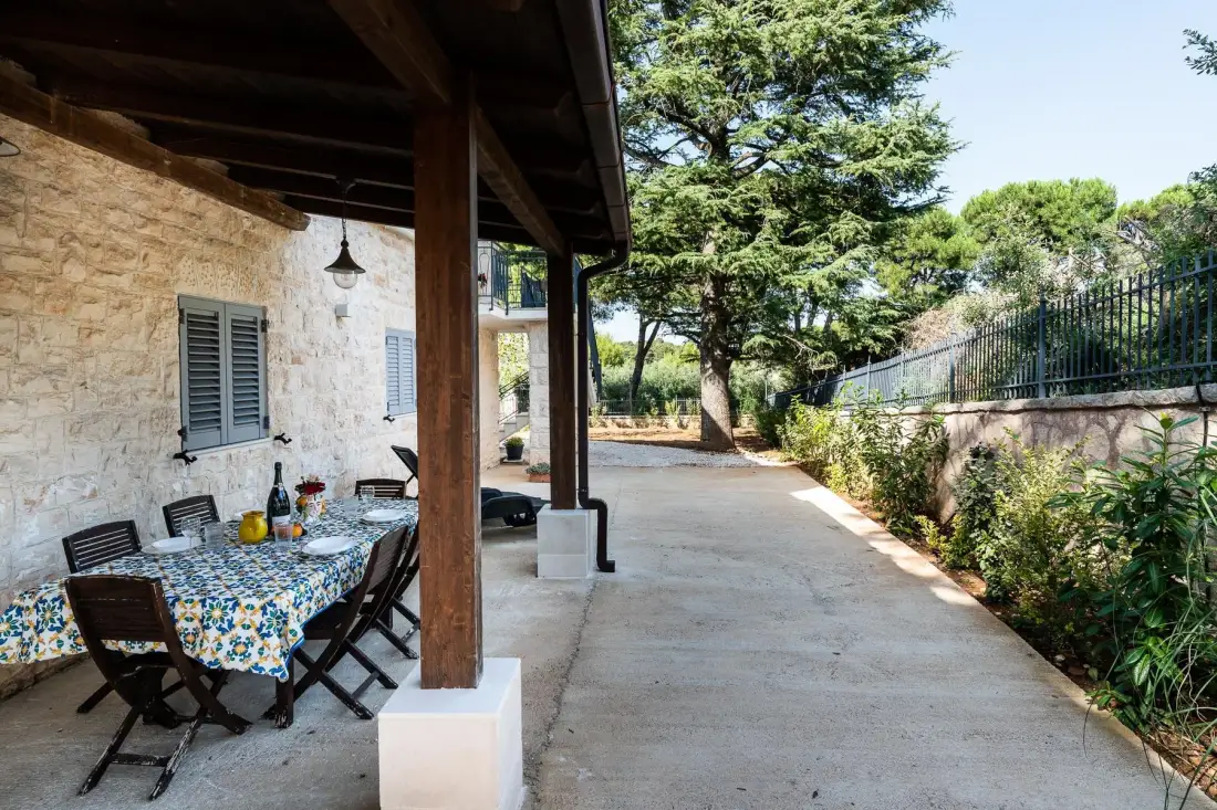 A covered outdoor dining area beside a stone building opens onto a paved path.