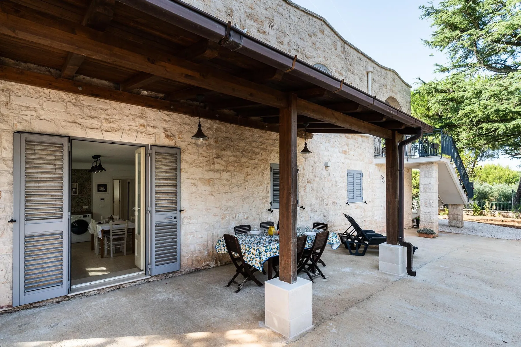 A covered stone patio with outdoor seating and an open doorway.