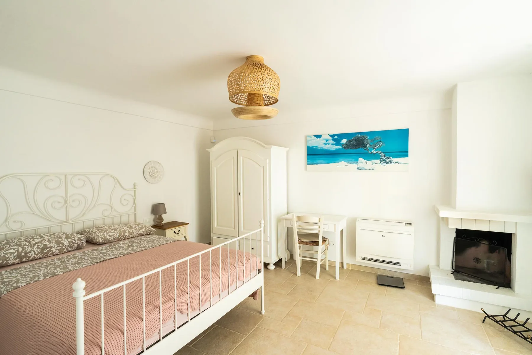 A bright bedroom with a white bed, a wardrobe, and a small dining table.