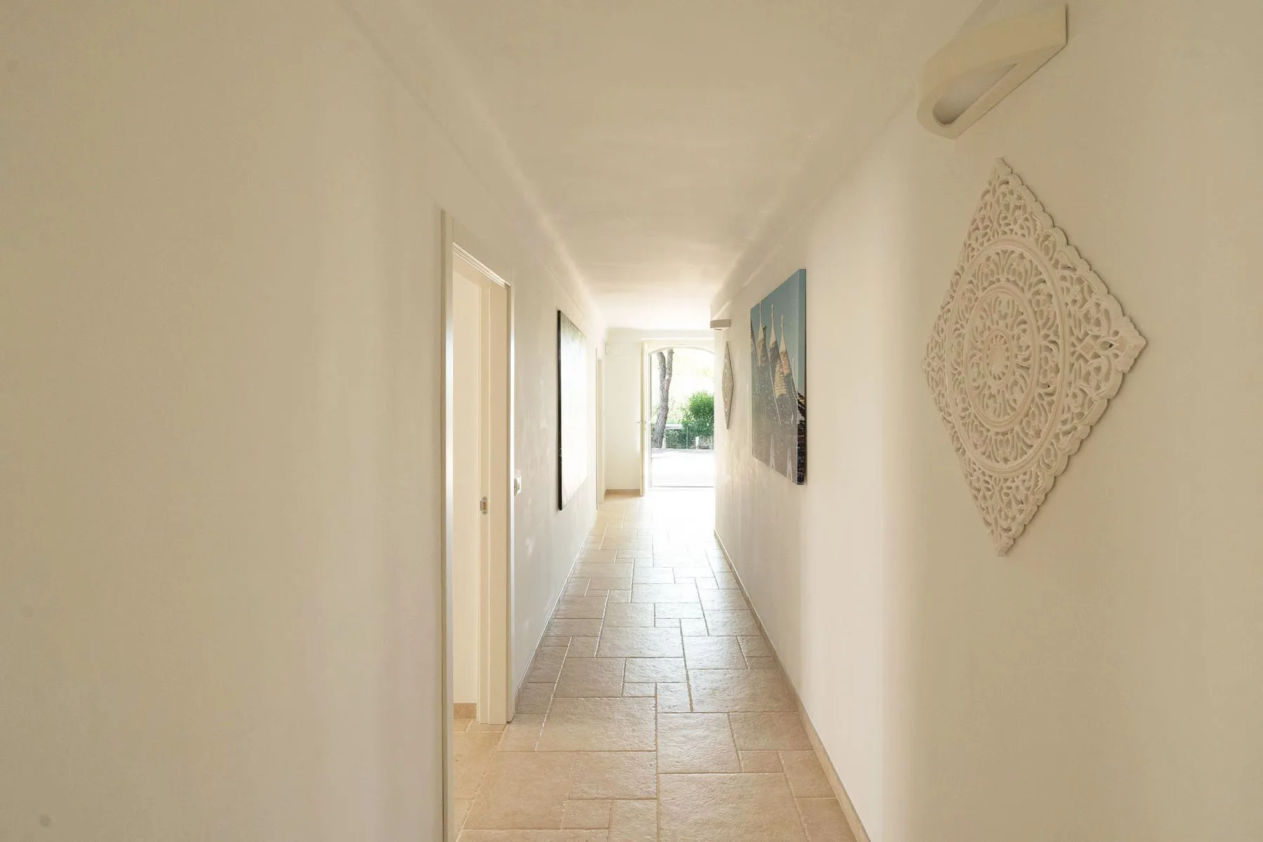 A bright interior hallway with tiled flooring and open doorways.