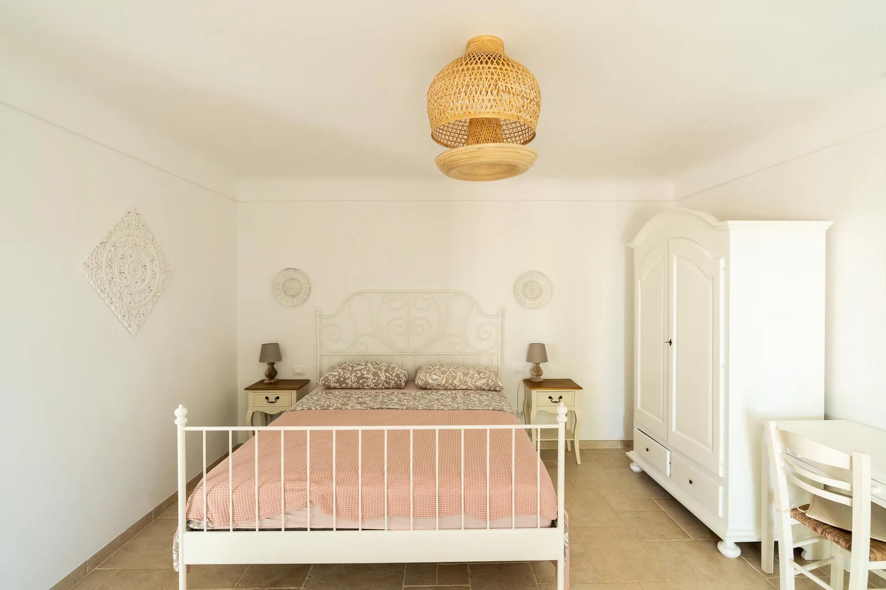 A bright bedroom with a bed and a white wardrobe.