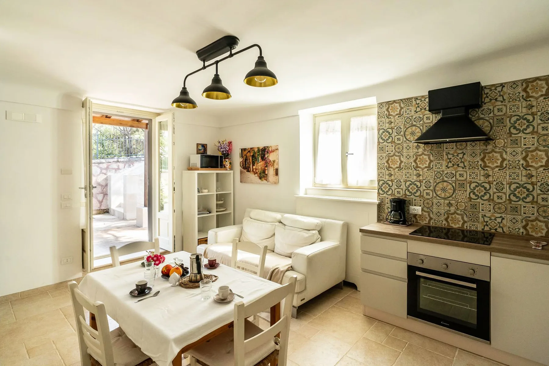 A dining area and kitchen share a bright room, with a table beside the cooking area.