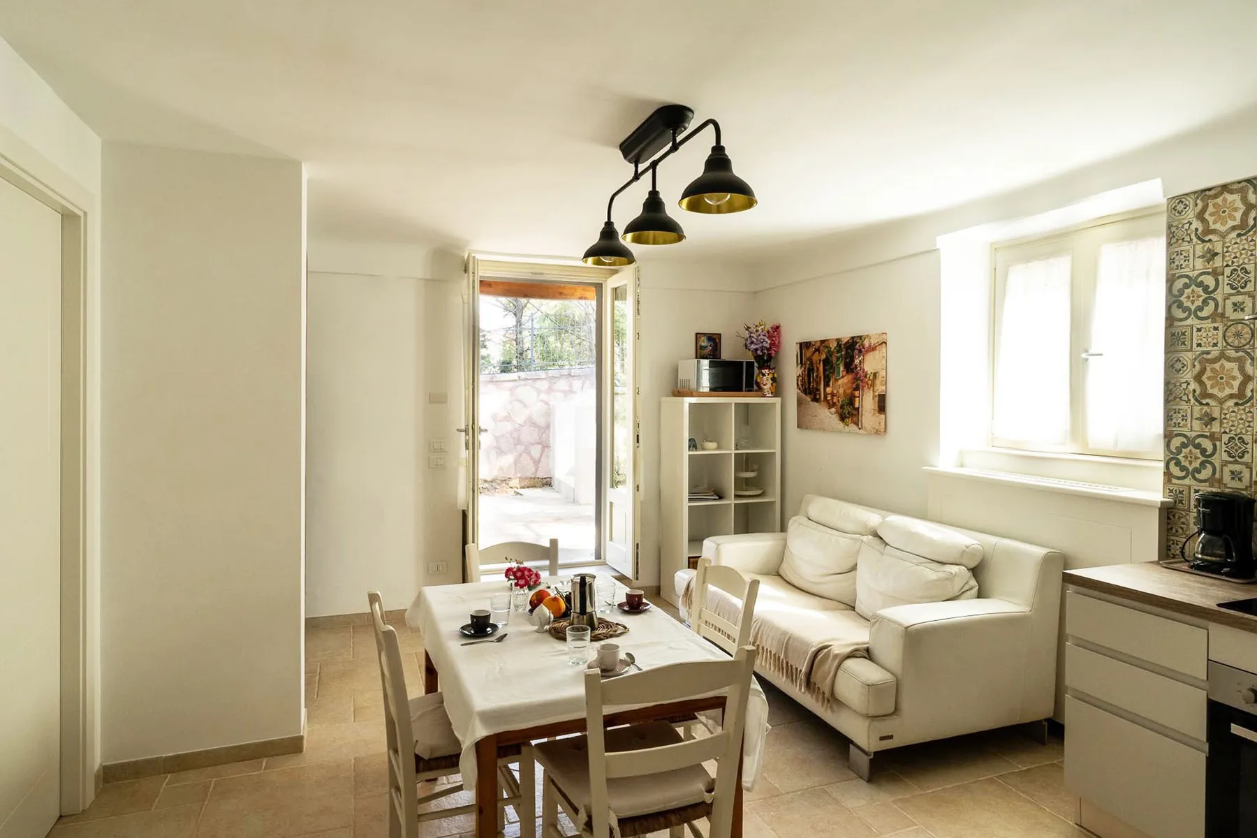 A bright living and dining area with seating, a table, and a window.