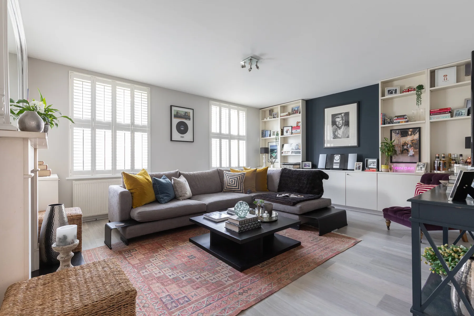 A bright living room with a sectional seating area, large windows, and built-in shelves.