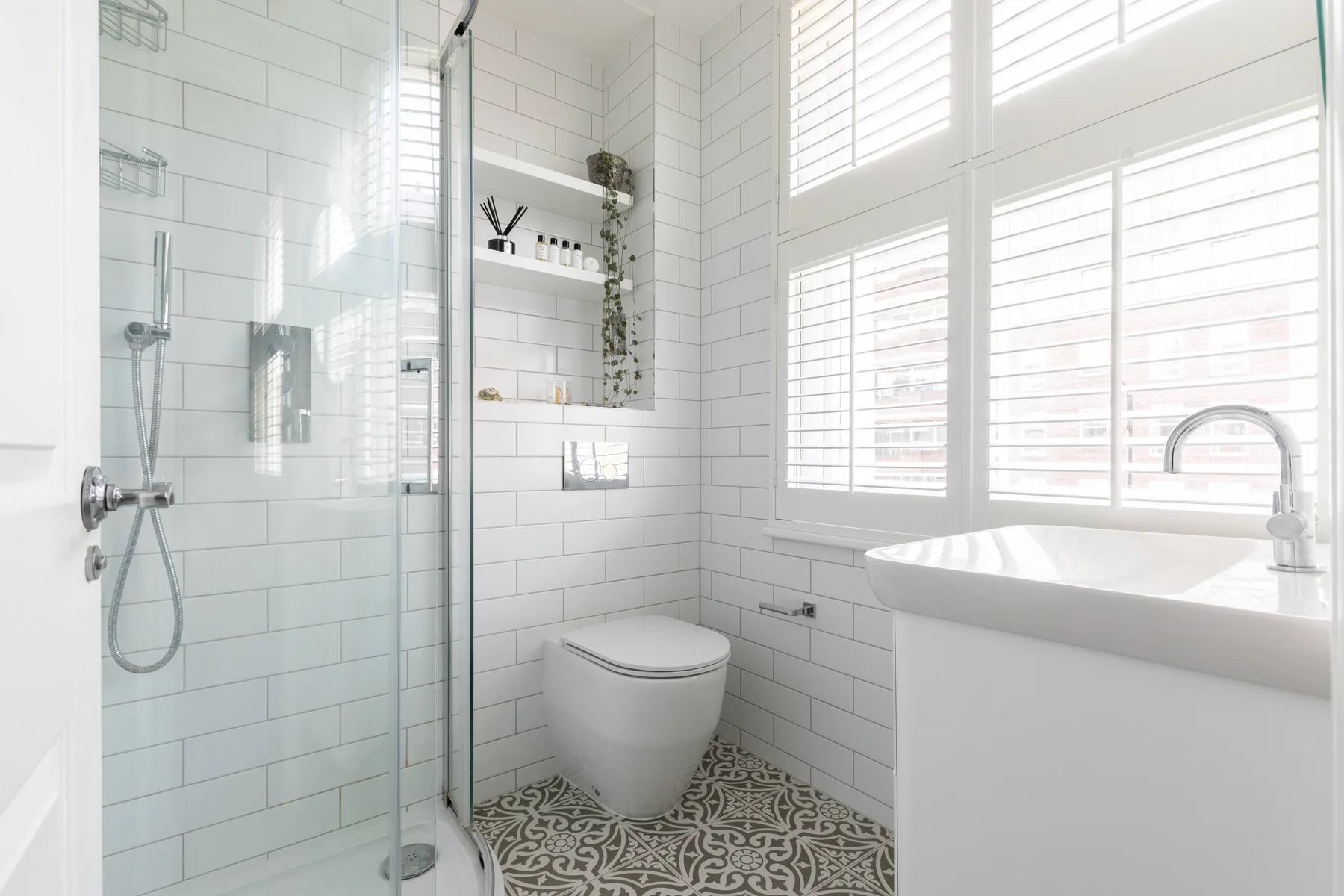 A bright bathroom with a glass shower, toilet, and large windows.