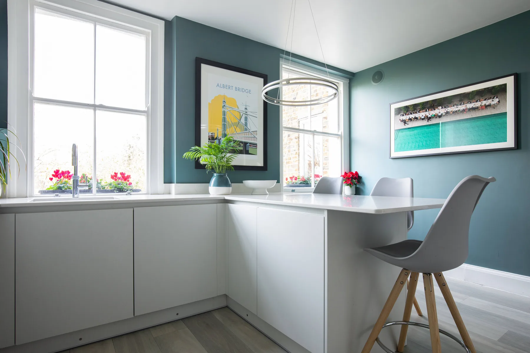 A bright home office with a long white desk beneath tall windows.