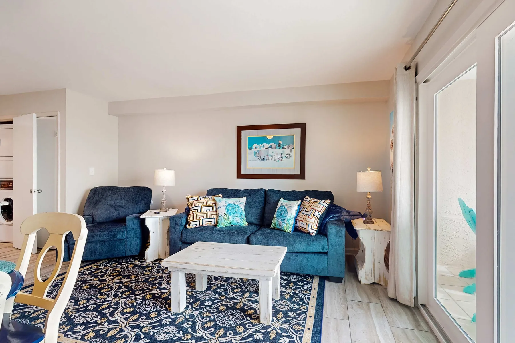 A living room with blue seating, a coffee table, and a patterned rug.