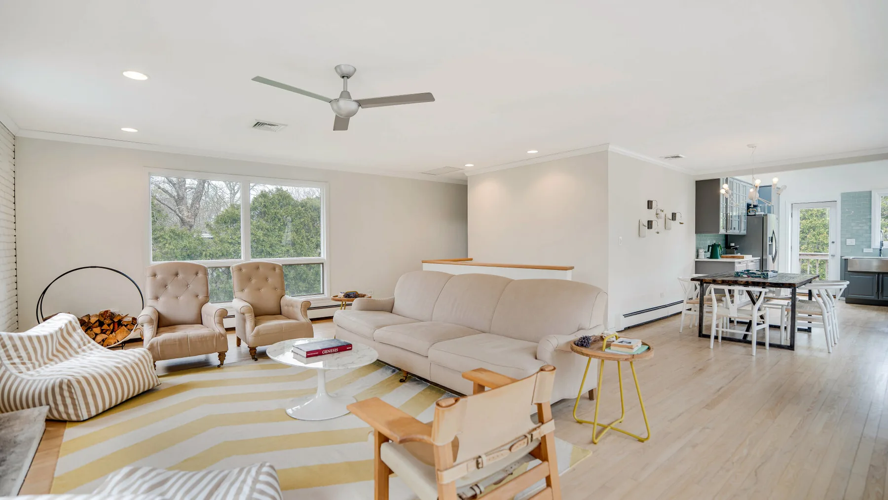 Una sala luminosa con asientos, ventanales y un comedor abierto.