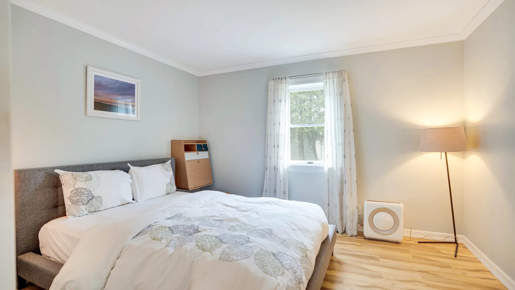 Un dormitorio con una cama, una ventana y una lámpara de pie.
