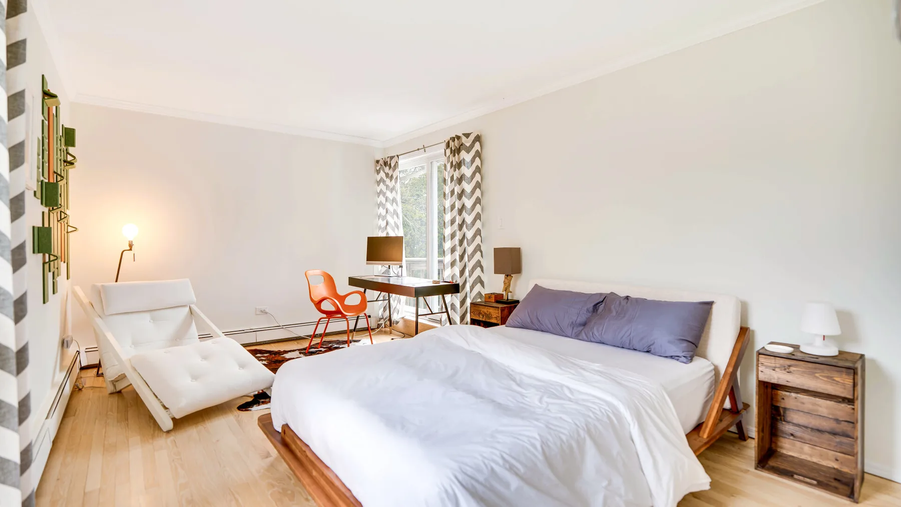 Un dormitorio luminoso con una cama grande, un escritorio y una silla de descanso.
