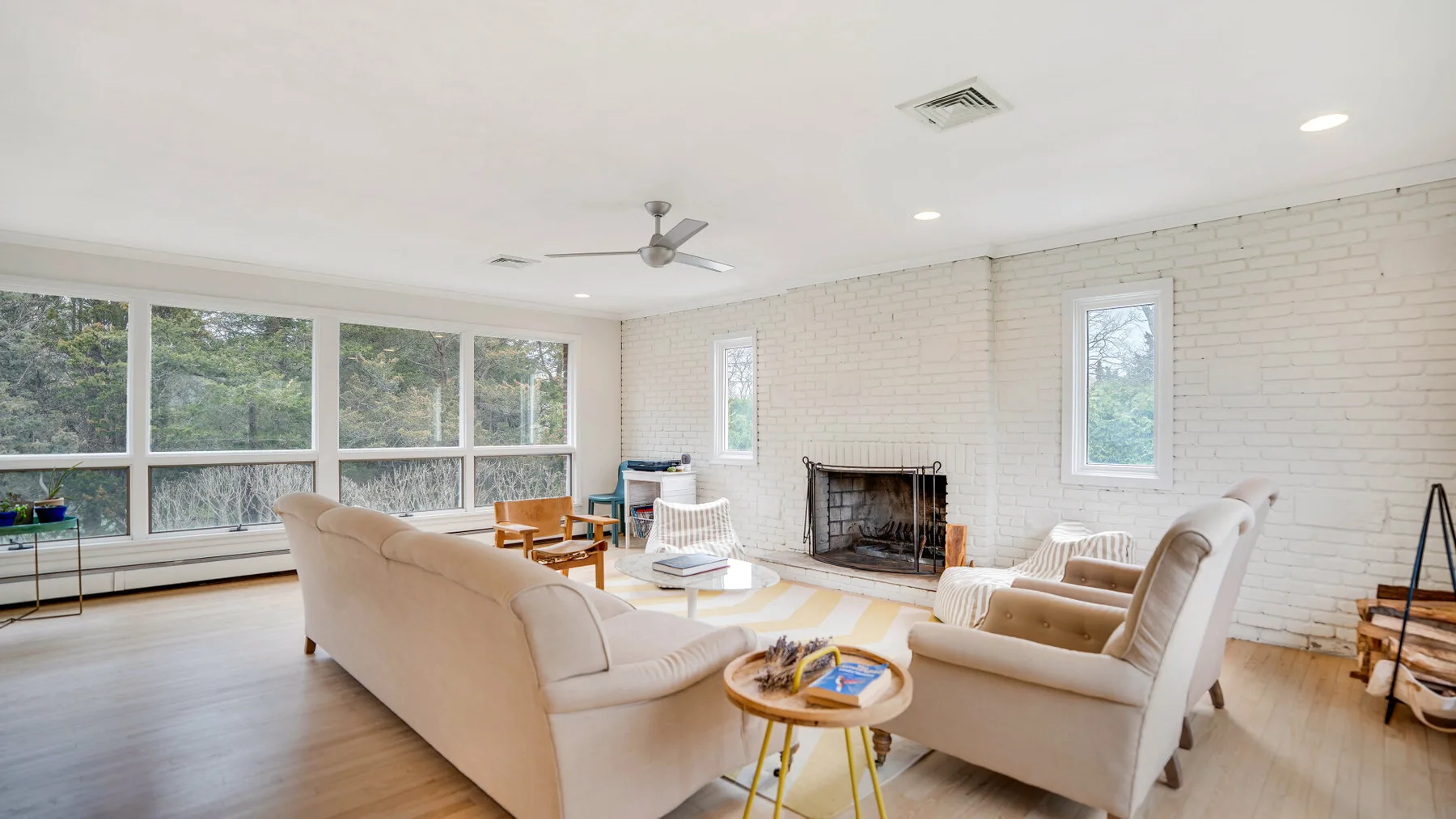 A bright living room with seating arranged around a fireplace and large windows.