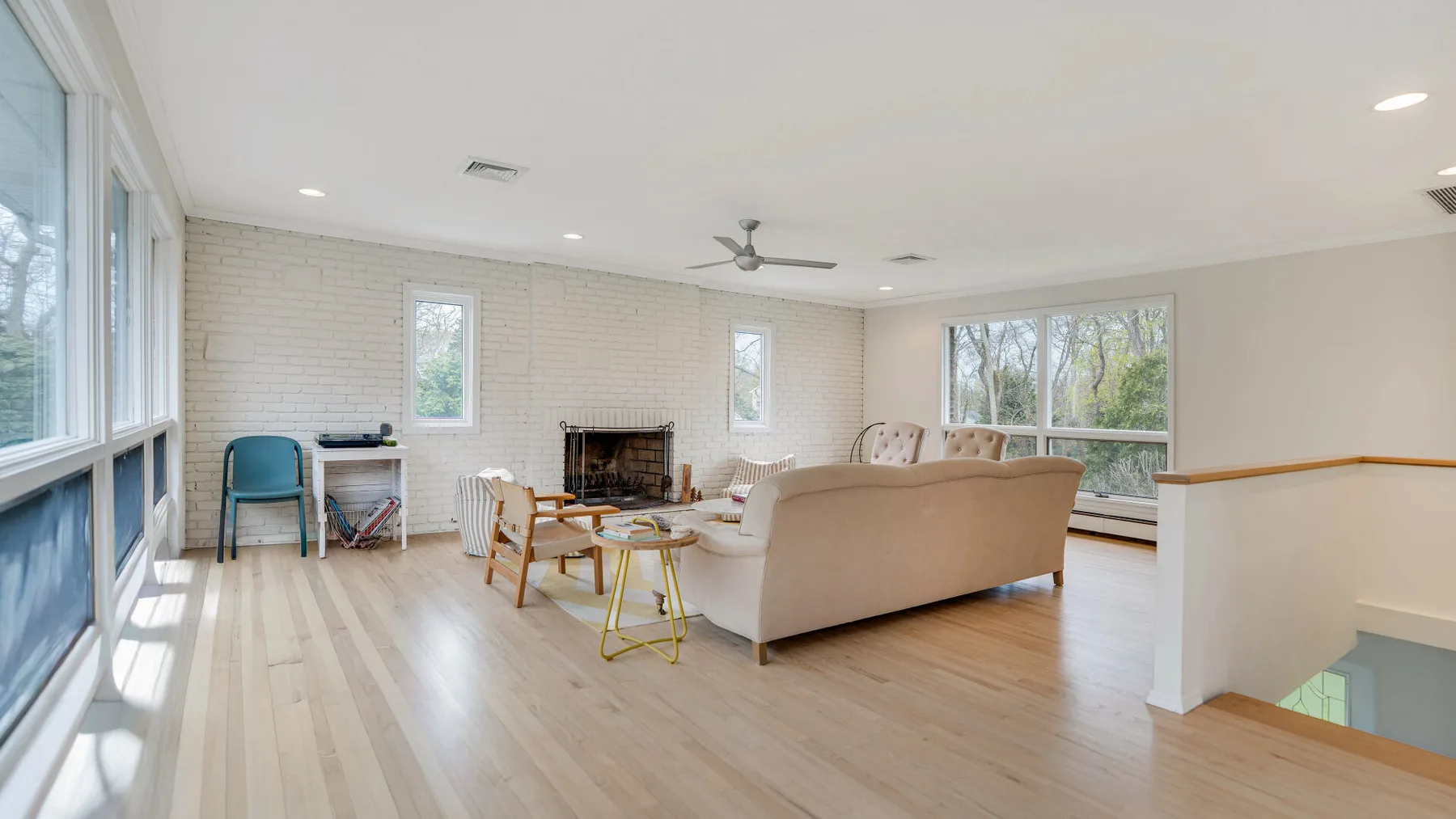 A bright living room with a fireplace, seating, and large windows.