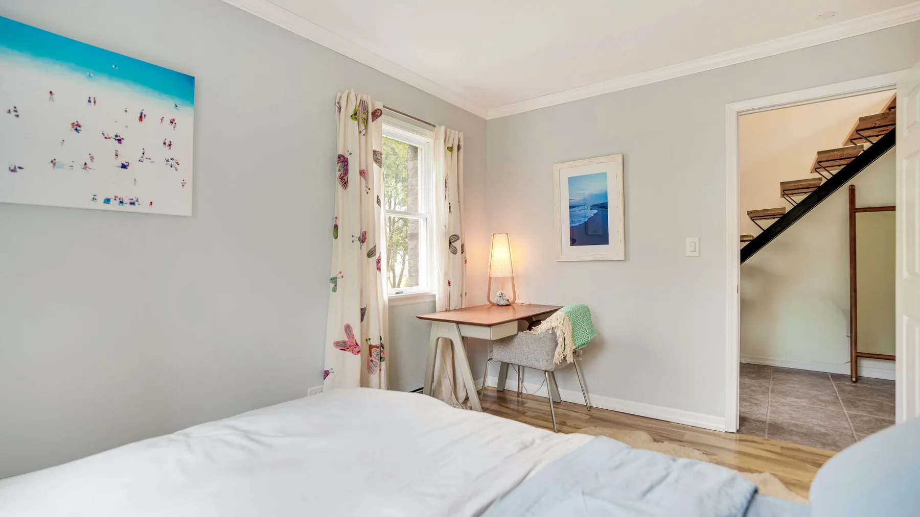 Un dormitorio con una cama y un pequeño escritorio junto a la ventana.