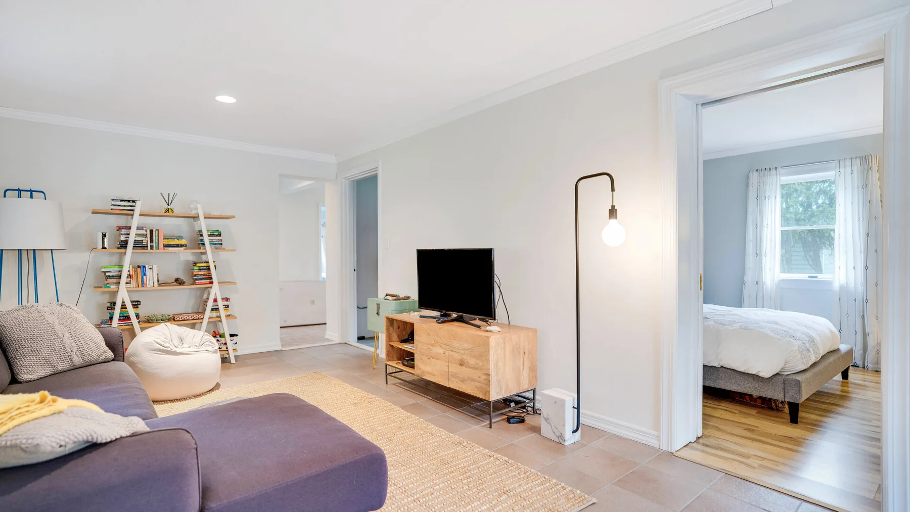 Una sala luminosa con asientos, un televisor y estanterías abiertas.