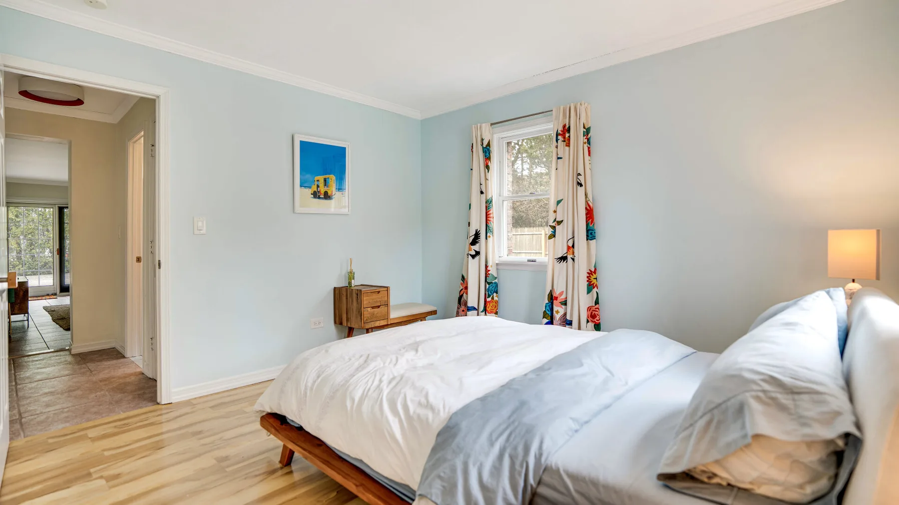 Un dormitorio con una cama, cortinas coloridas y paredes azul claro.
