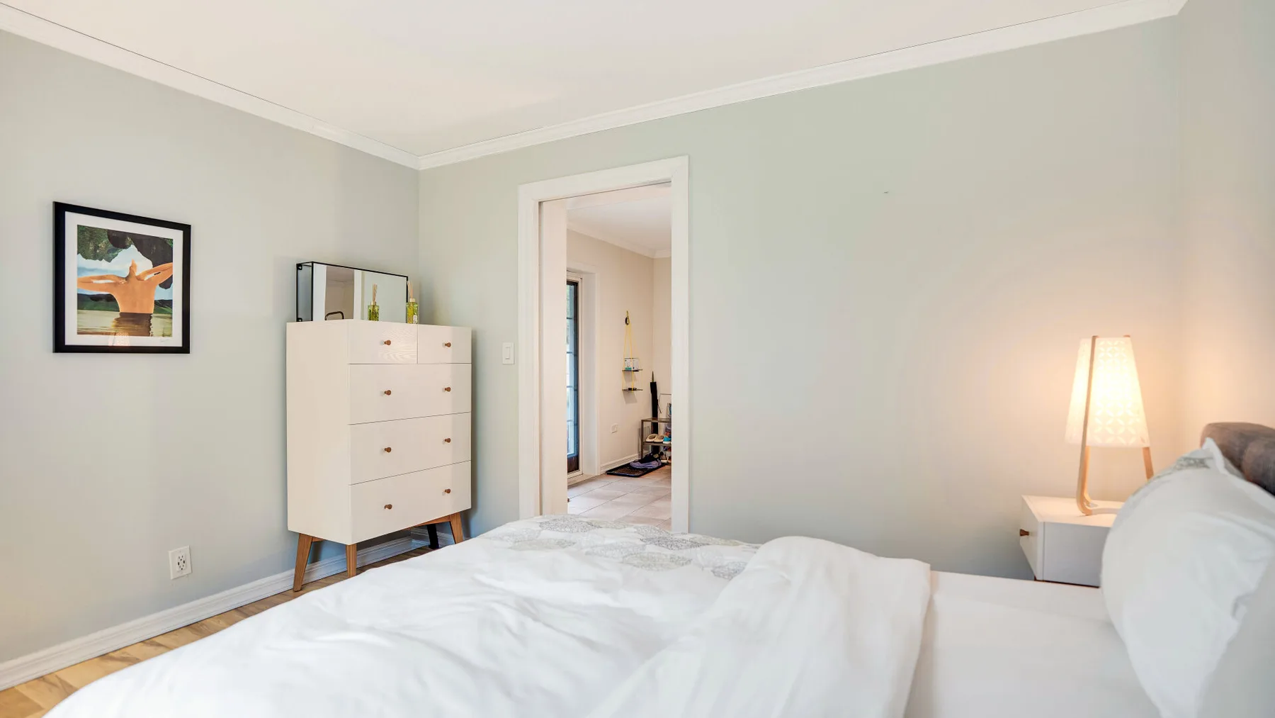 Un dormitorio con una cama tendida, una cómoda y una puerta.