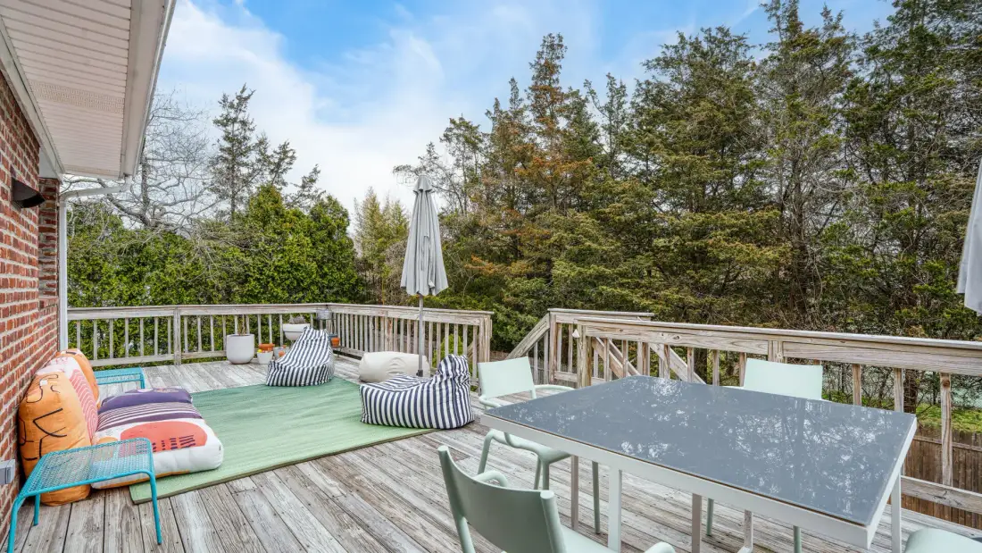 Una terraza exterior tiene una mesa, asientos y cojines de colores.