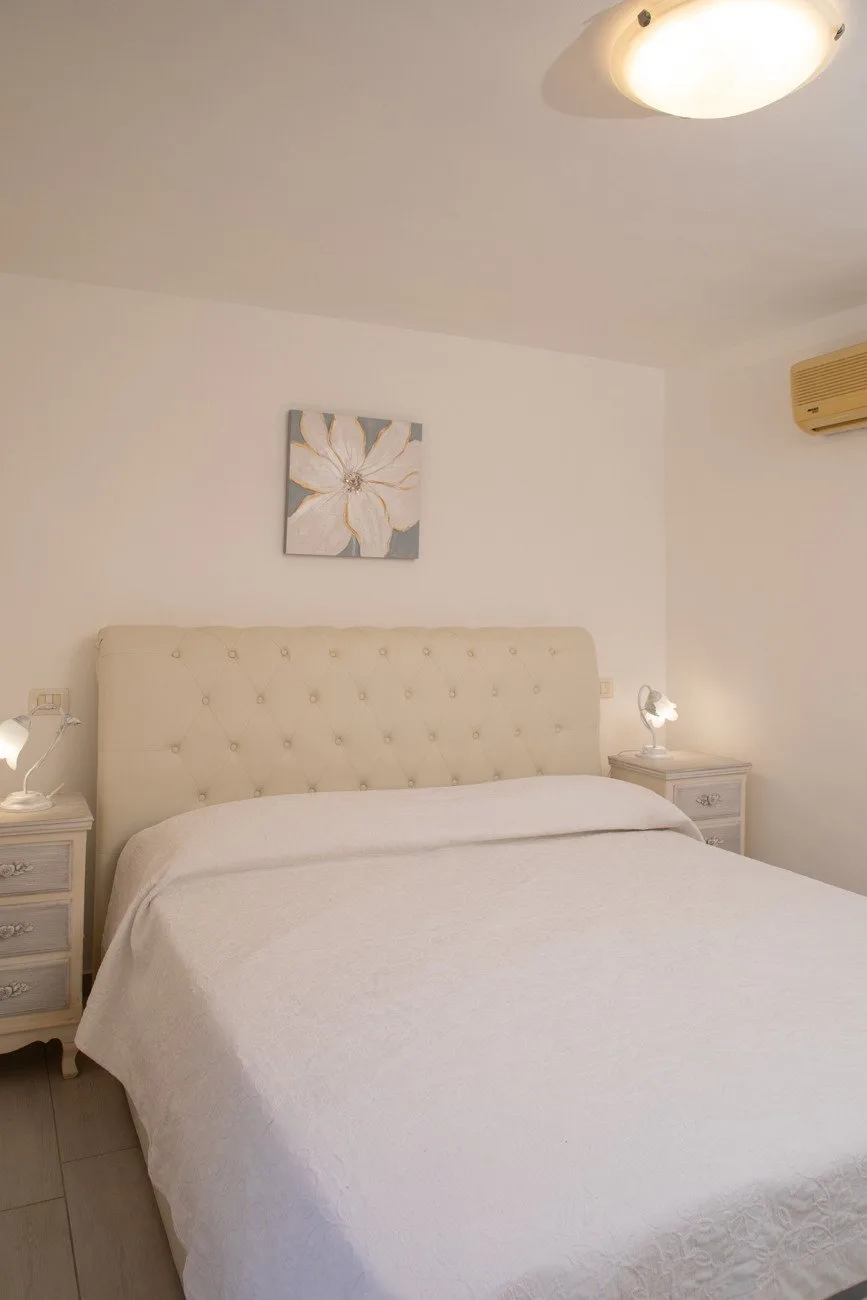 A bedroom with a bed beneath a floral wall picture.
