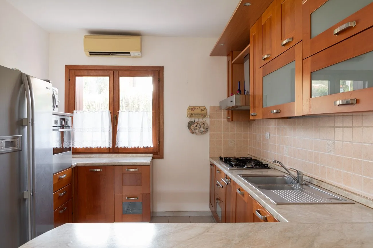A kitchen with wooden cabinets, a refrigerator, and a countertop.