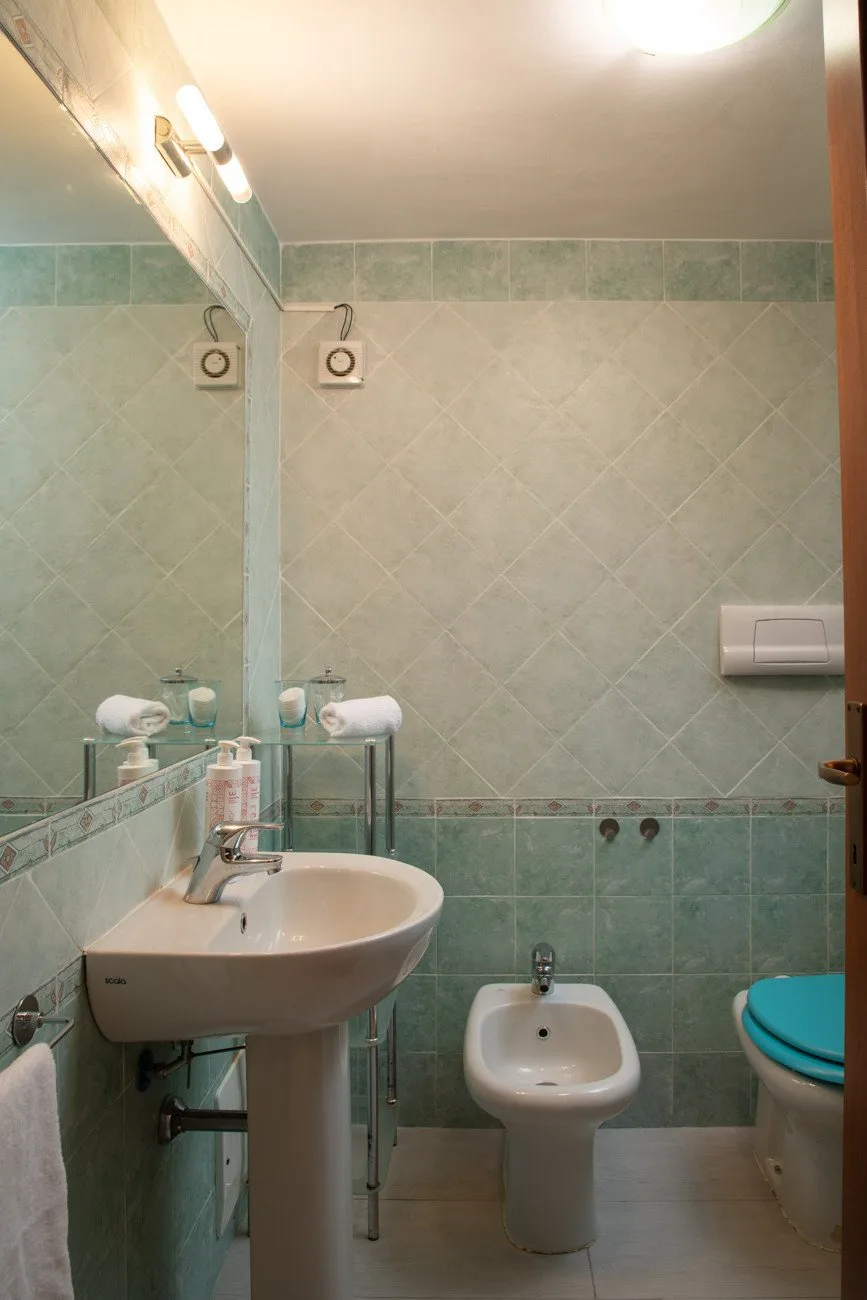 A bathroom with a sink, bidet, and toilet.