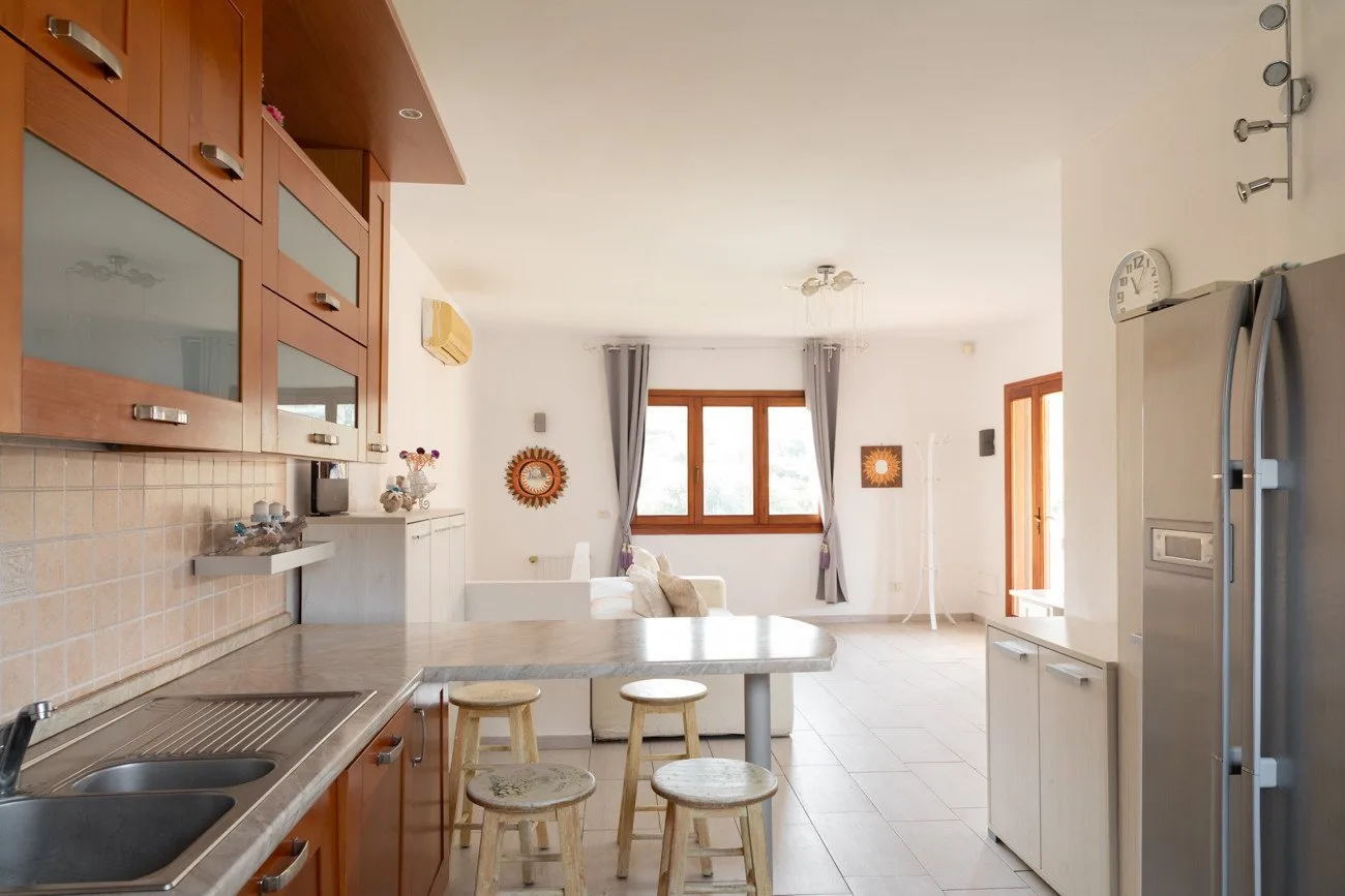 Una cocina luminosa con una encimera central, gabinetes de madera y una ventana.
