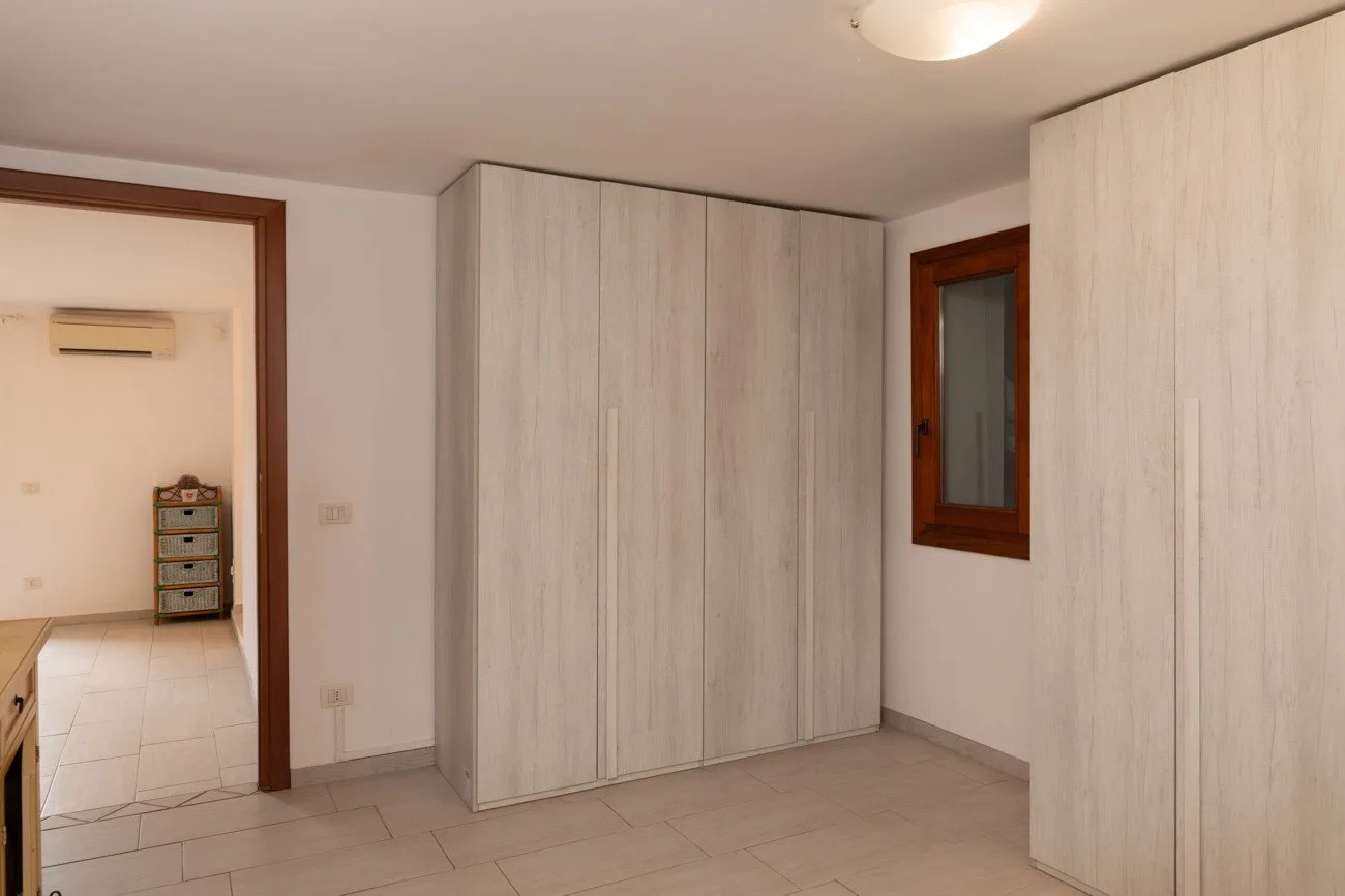 A room with large light-colored wardrobes and a small window.