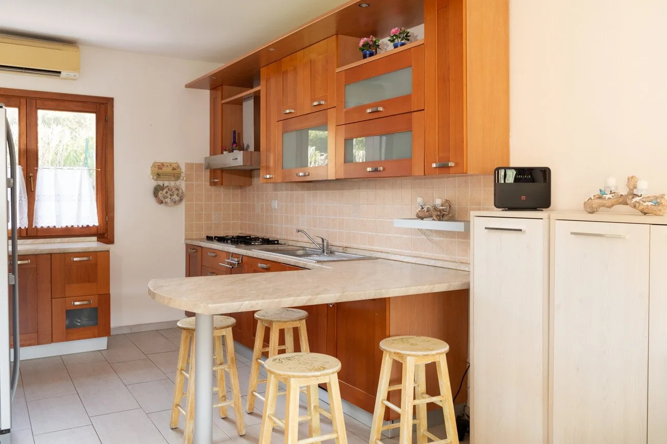 A bright kitchen with wooden cabinets and a counter with stools.