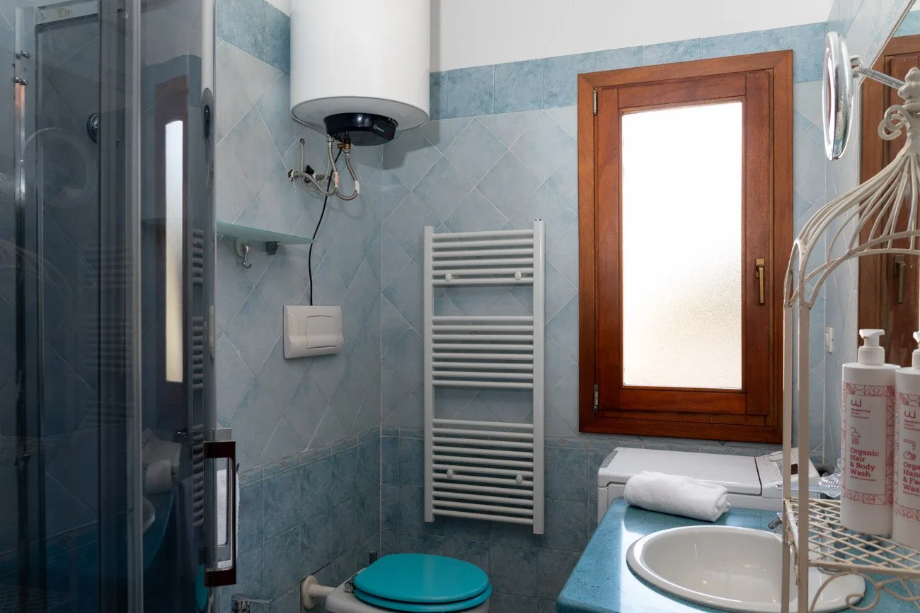 A tiled bathroom with a shower, sink, and frosted window.