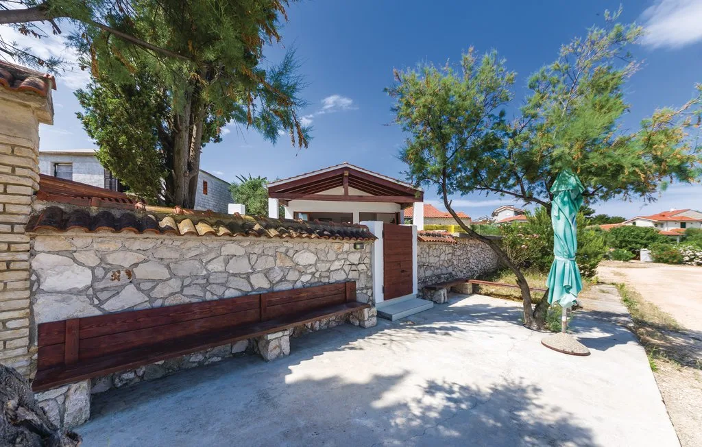 A stone-walled outdoor entrance with a wooden bench and a small covered gate.