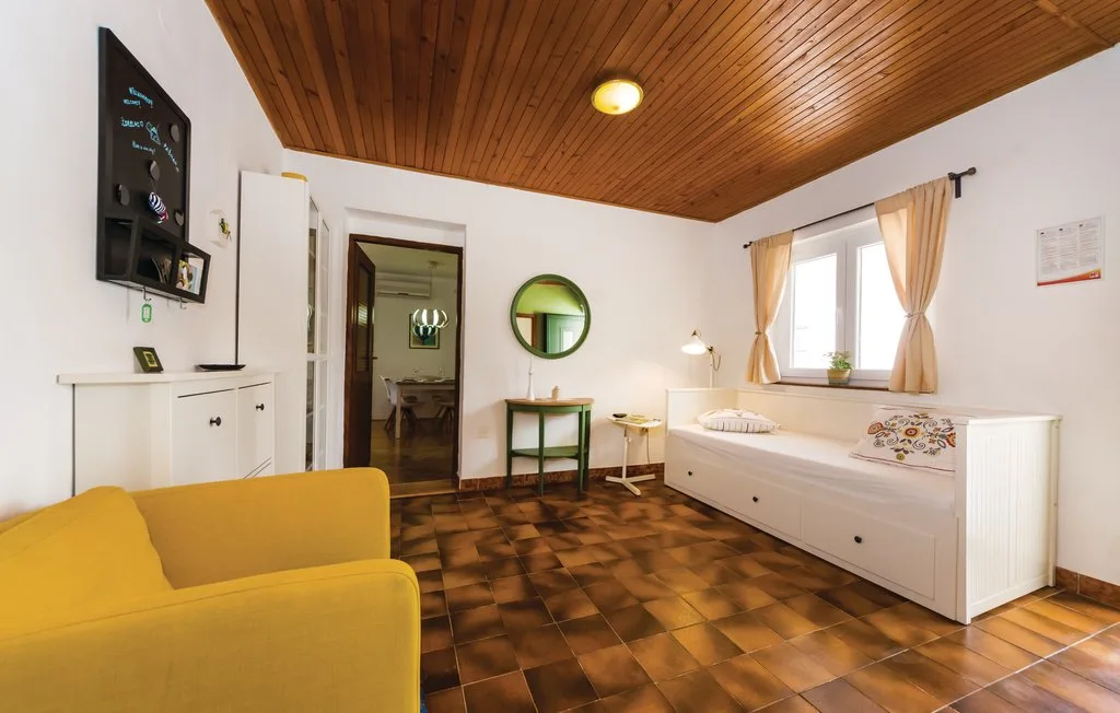 A bedroom with a bed, a yellow sofa, and a wooden ceiling.