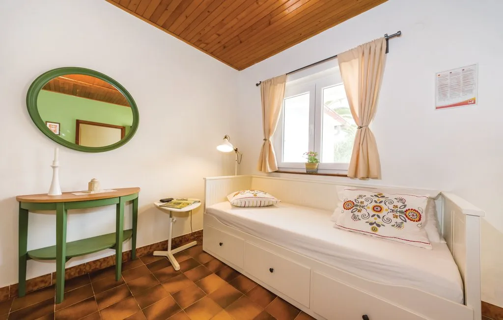 A bright sitting area with a daybed beneath a window and a small table.